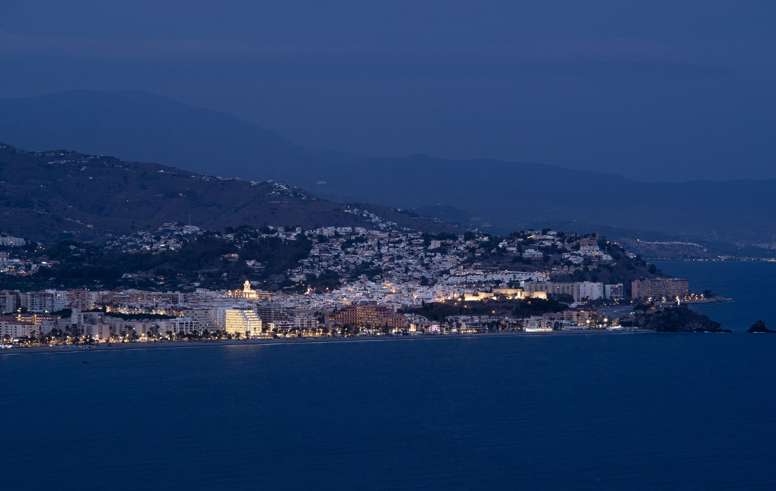 Stunning view of Granada's coastline and illuminated cityscape at night, capturing natural beauty and vibrant city life.